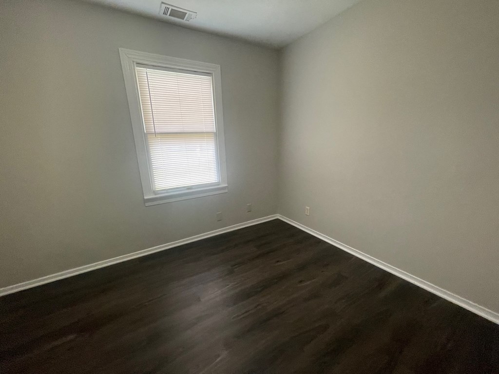 A room with a window and wooden flooring.
