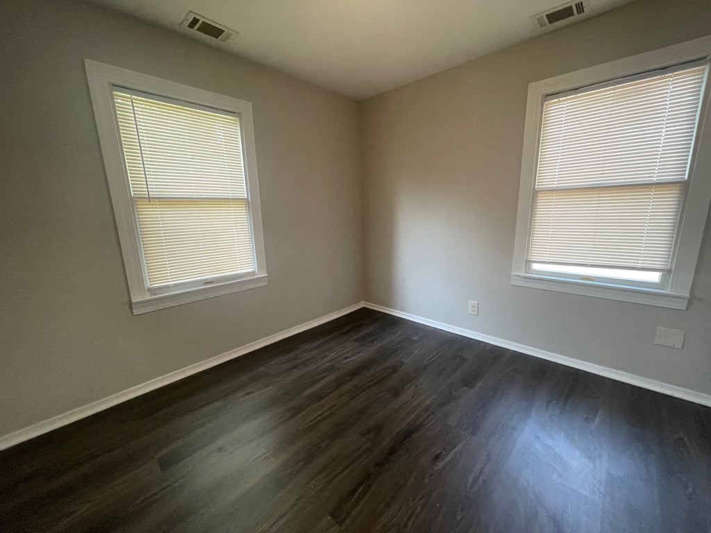 A room with two windows and wooden flooring.