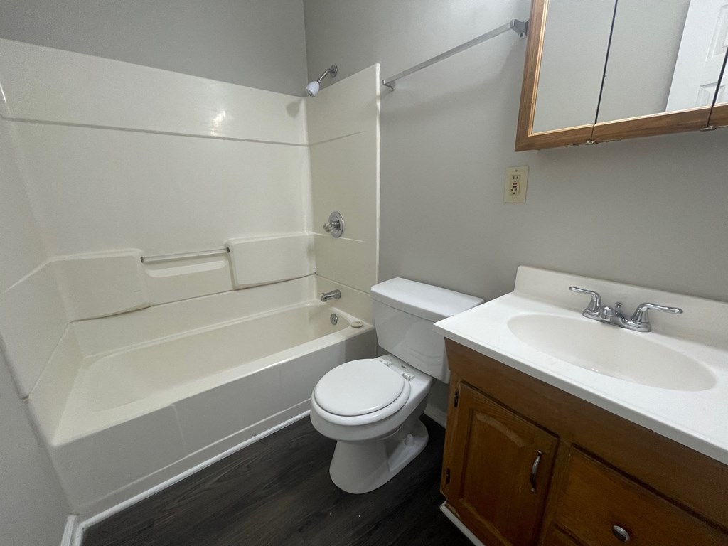 A white toilet sits in a bathroom next to a bathtub.