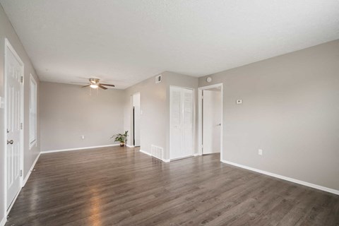 an empty living room with wood floors and a ceiling fan