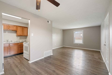 an empty living room and kitchen with wood floors and a ceiling fan