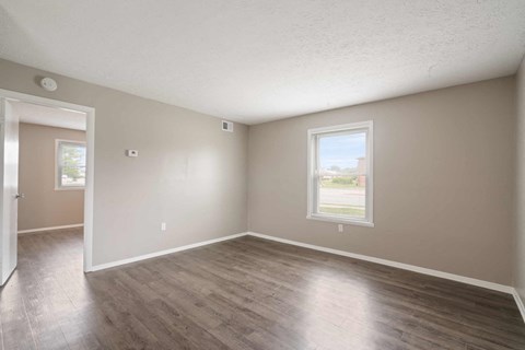 an empty living room with wood floors and a window