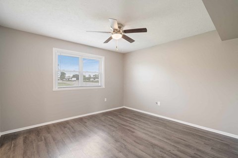 an empty bedroom with a ceiling fan and a window