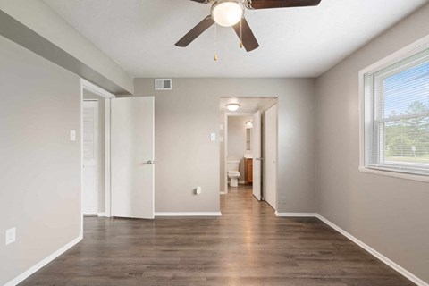 a living room with a ceiling fan and a hallway to a bathroom