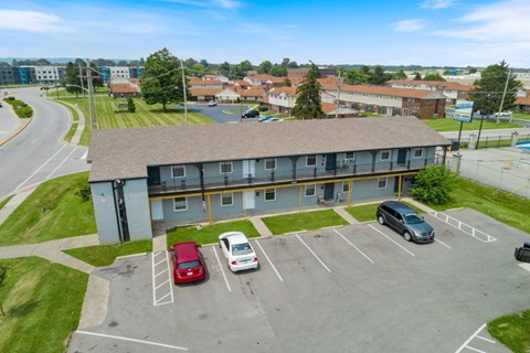 an aerial view of an apartment building in a parking lot with parked cars