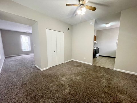 an empty living room with carpet and a ceiling fan