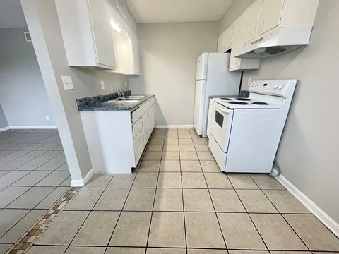 an empty kitchen with white appliances and white cabinets