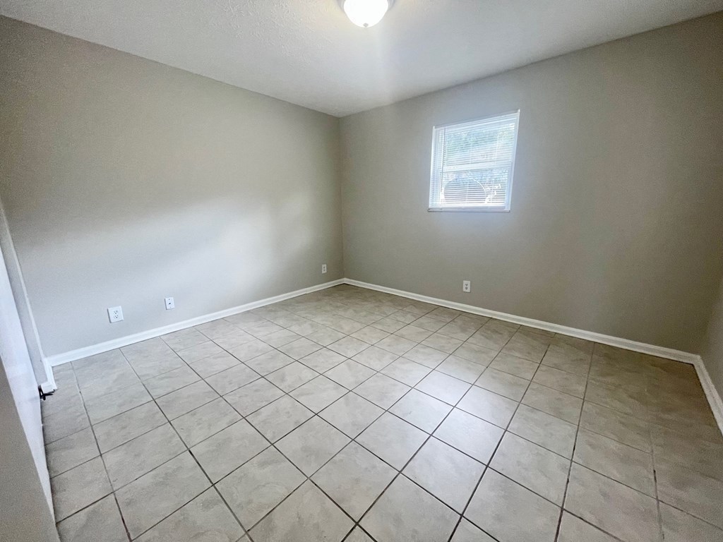 an empty living room with tiled floors and a window