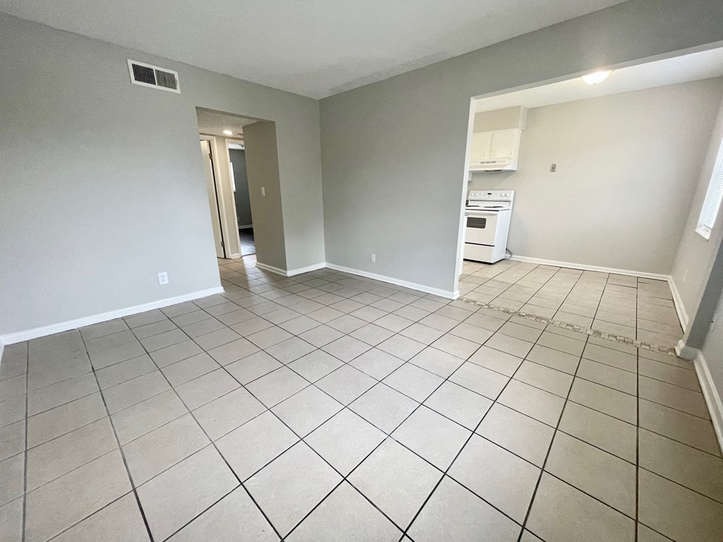 the living room and kitchen of an empty house with tiled flooring