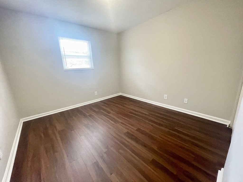 an empty room with wooden floors and a window