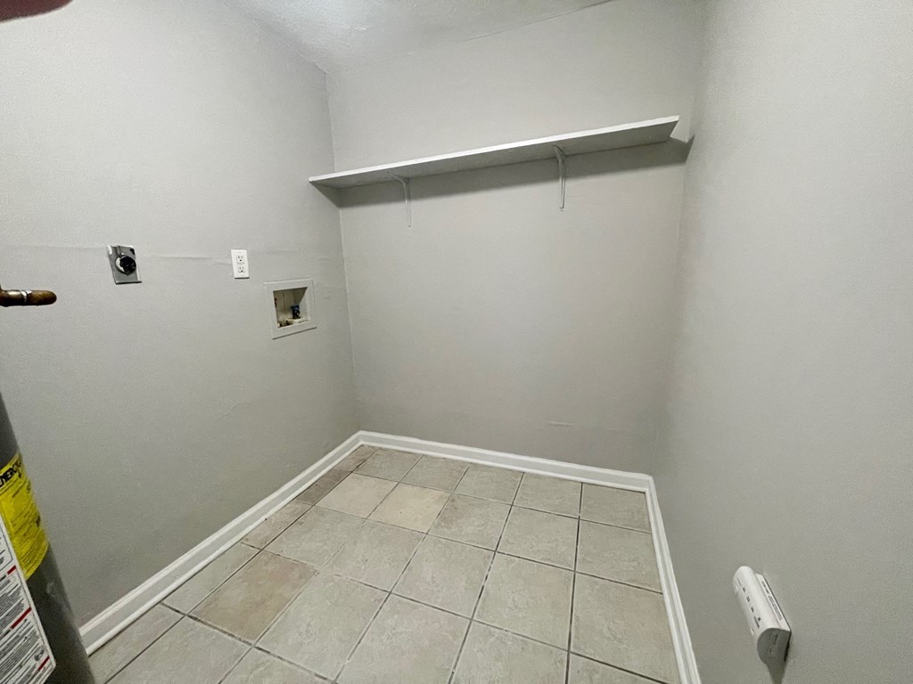 a room with a white wall and a tile floor and a closet