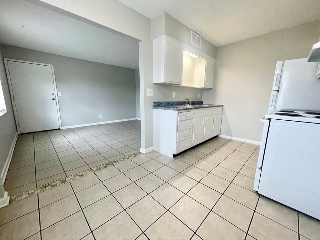 an empty kitchen with a tiled floor and white appliances