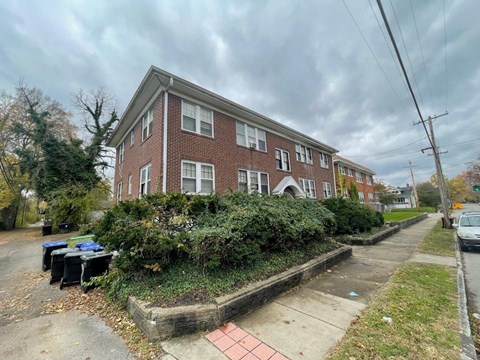 A red brick building with a green bush in front.