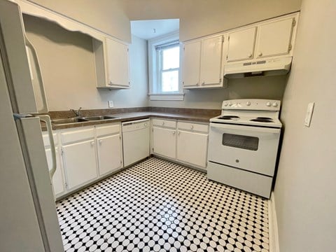 a kitchen with black and white checkered floor and white appliances