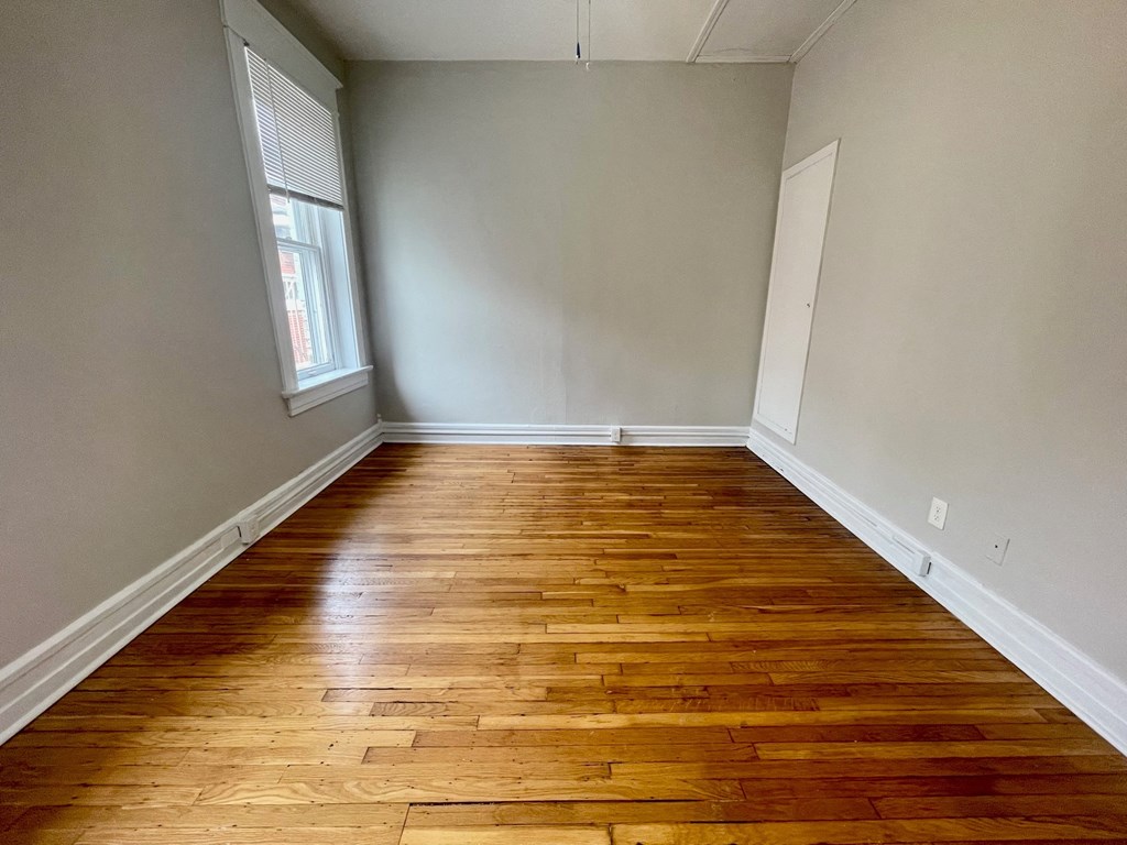 an empty room with wooden floors and a window
