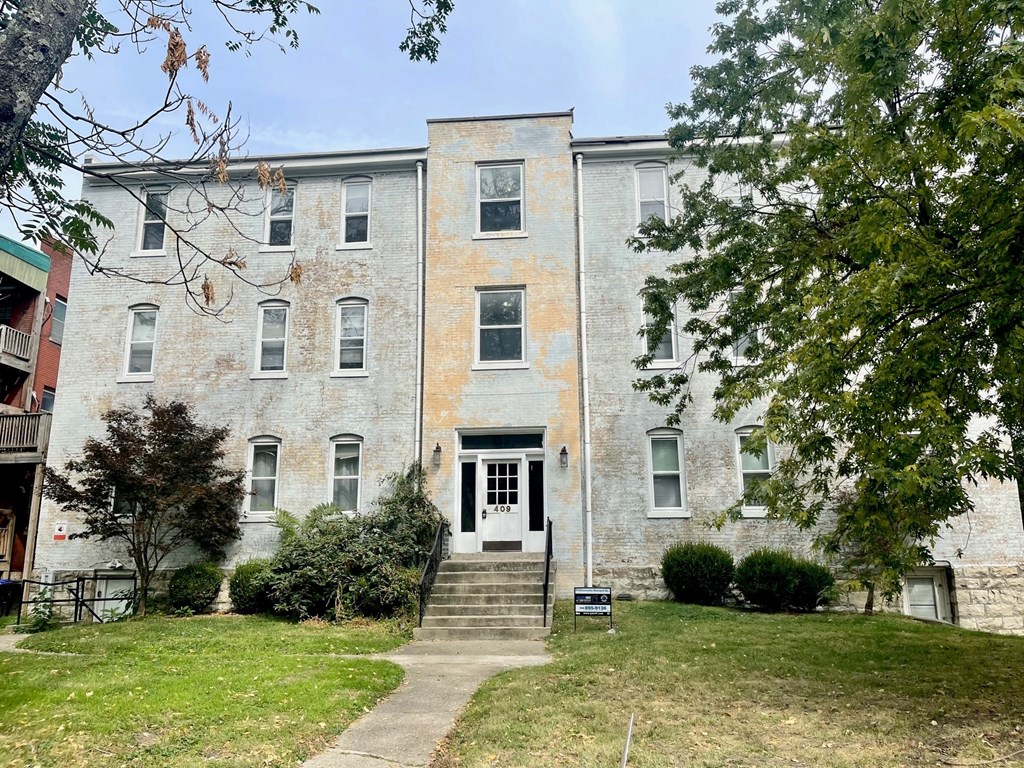 an old brick building with steps and a lawn