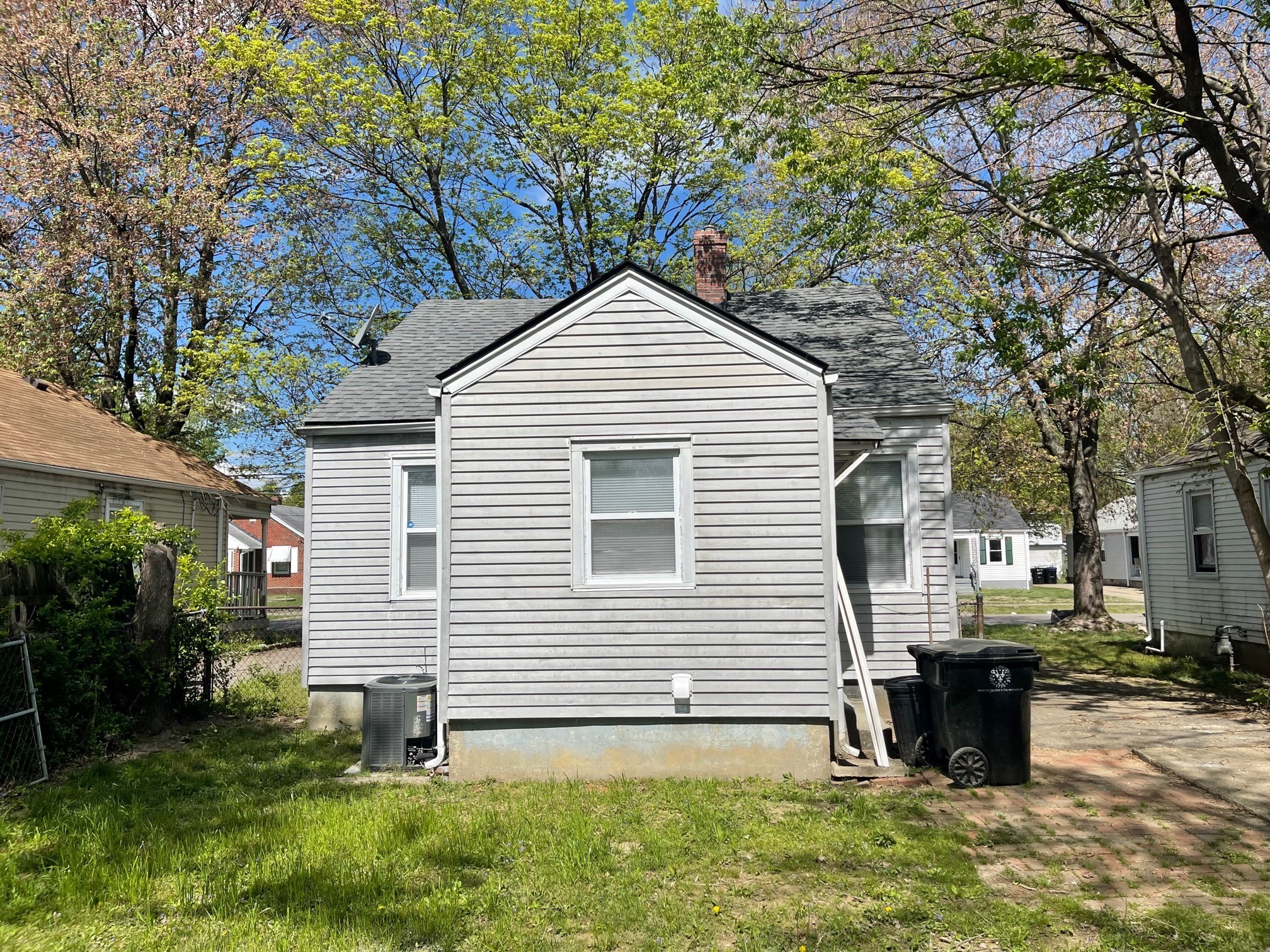 the back of a house with a trash can in front of it
