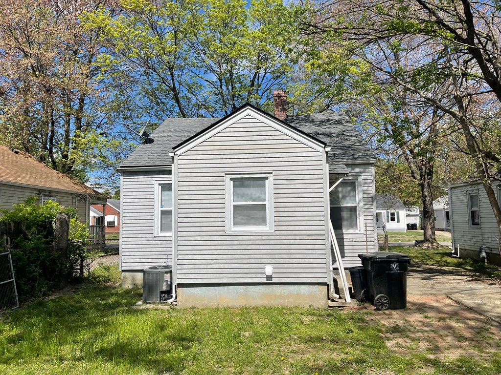 the back of a house with a trash can in front of it
