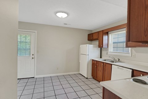 an empty kitchen with white appliances and wooden cabinets