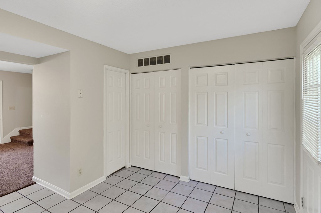 the living room has three closets and a tiled floor