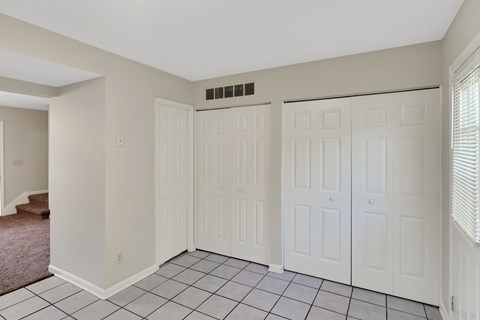 the living room has three closets and a tiled floor