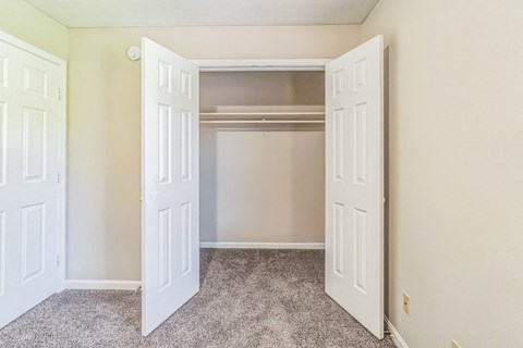 an empty bedroom with two doors and a closet