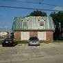 a building with a green roof and two cars in front of it