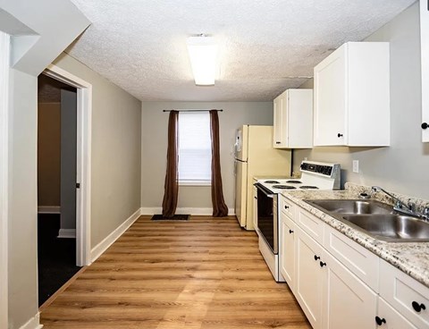 A kitchen with white cabinets and a wooden floor.