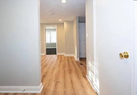 A hallway with a white door and a grey door on the other side.