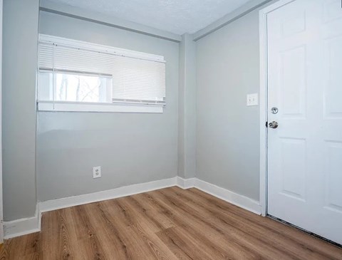 A room with a white door and a window with blinds.