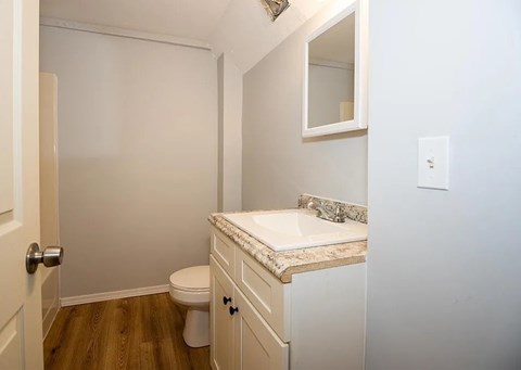 A white bathroom with a toilet, sink, and mirror.