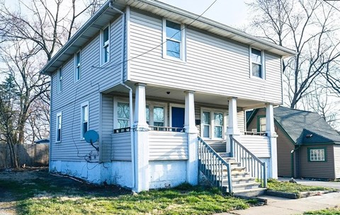 A two-story house with a front porch and stairs leading up to the door.