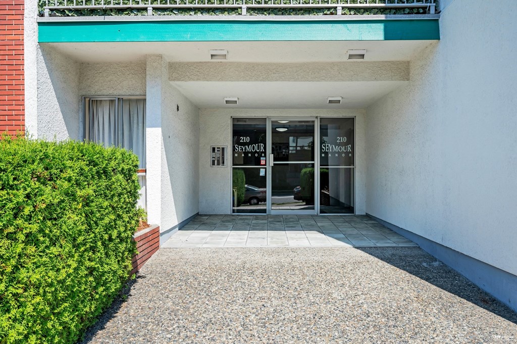 The image shows the front of a building with a glass door and a sign that reads "210 SEYMOUR".