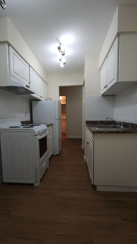 A kitchen with white cabinets and a wooden floor.