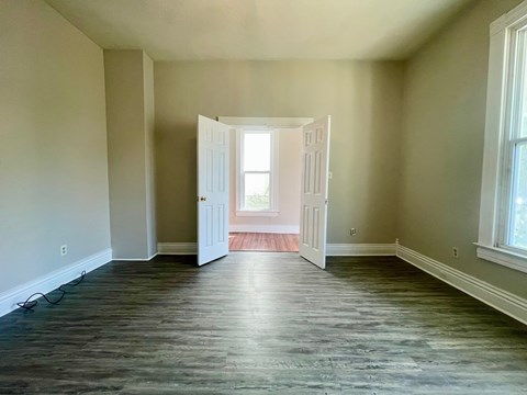 A room with a wooden floor and a doorway leading to another room.