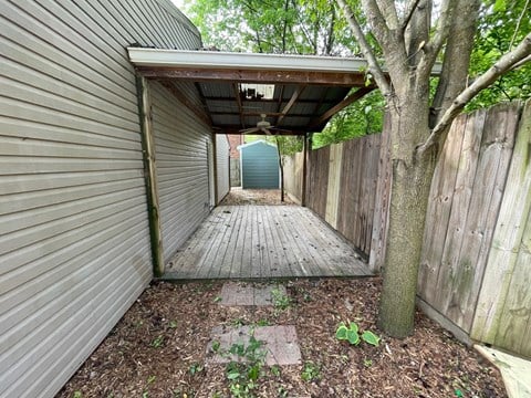 a covered walkway with a tree and a blue door