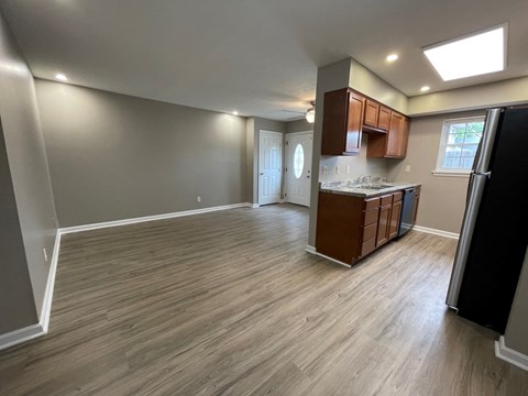 an empty living room and kitchen with wood flooring