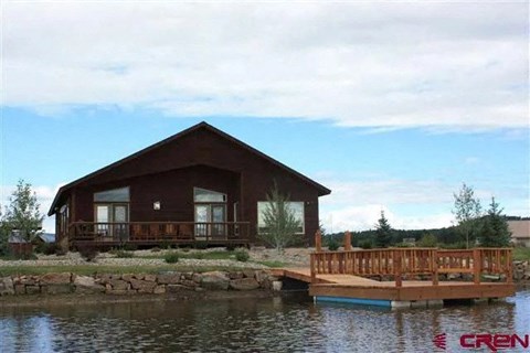 A house with a deck is situated by a body of water.