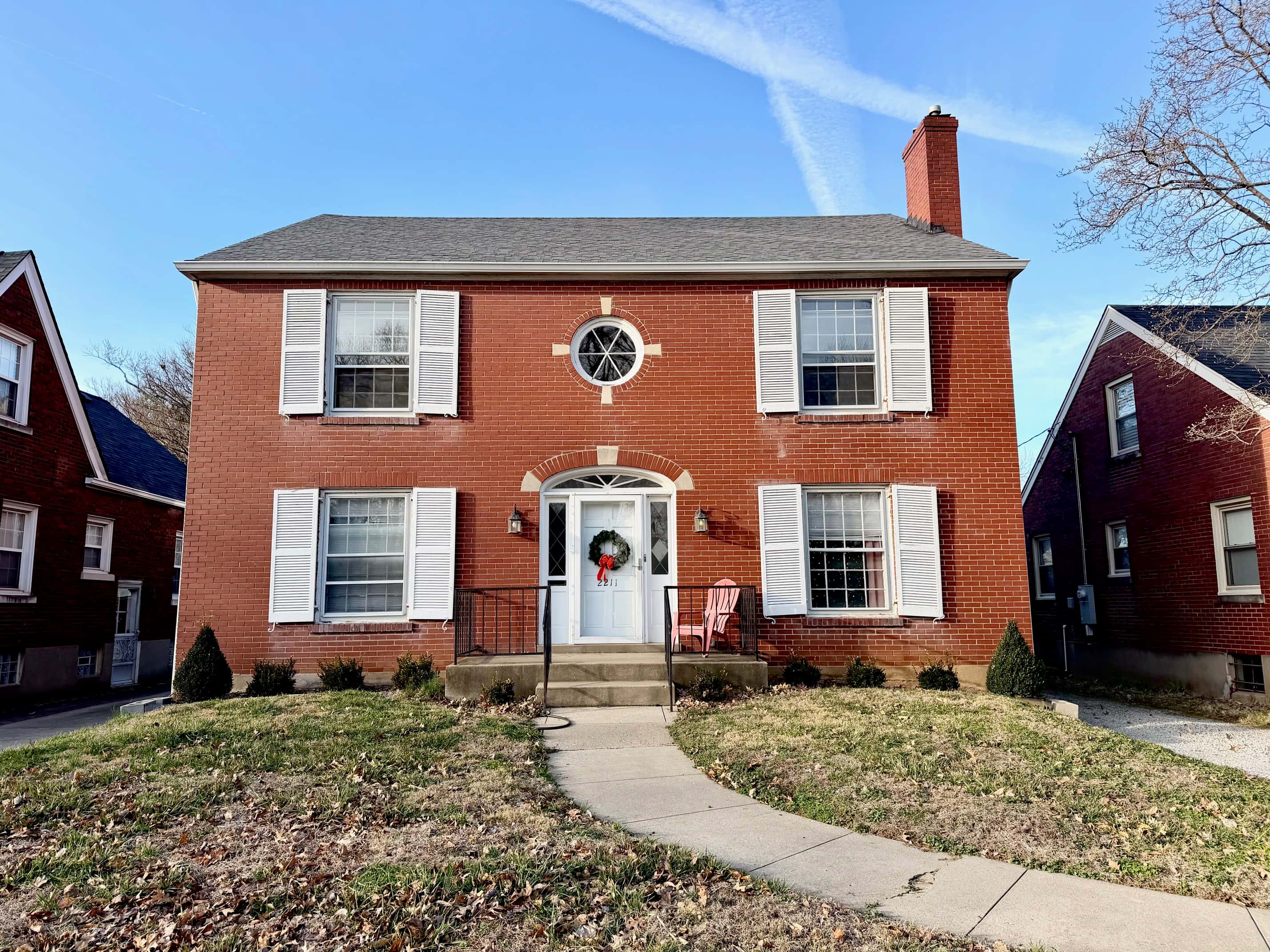 A red brick house with a white door and windows.