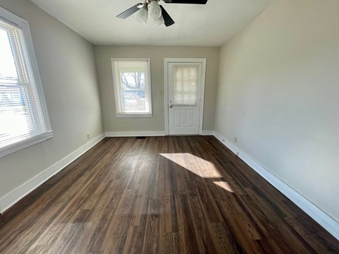 an empty living room with hardwood floors and white walls