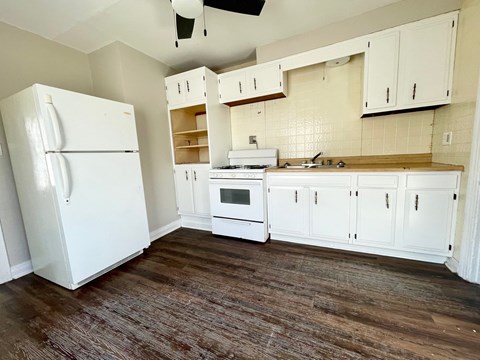 an empty kitchen with white appliances and white cabinets