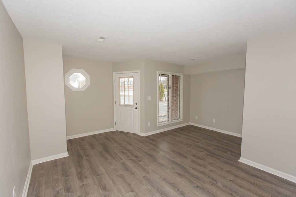 an empty living room with wood flooring and a door to a patio
