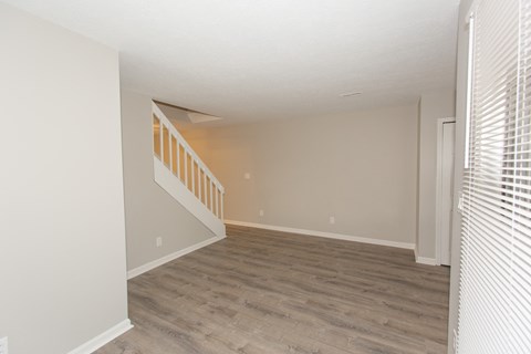 an empty living room with wood floors and a white staircase