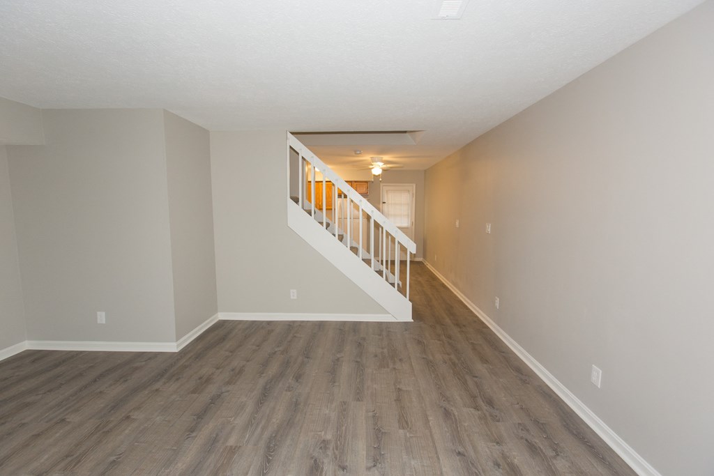 an empty living room with wooden floors and a staircase
