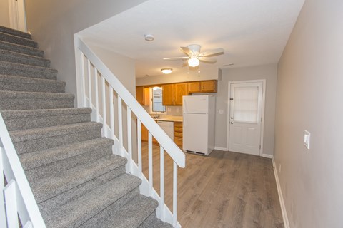 the view from the bottom of the stairs looking into the kitchen andoyer of a