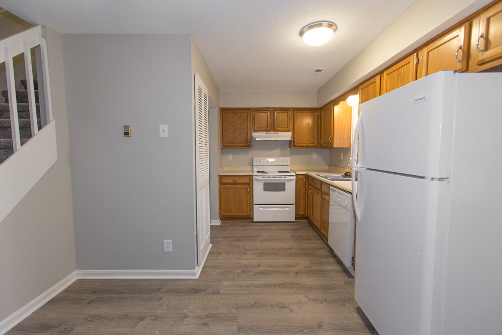 an empty kitchen with white appliances and wooden cabinets