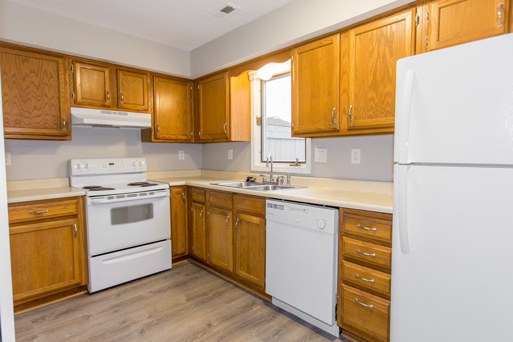 an empty kitchen with white appliances and wooden cabinets