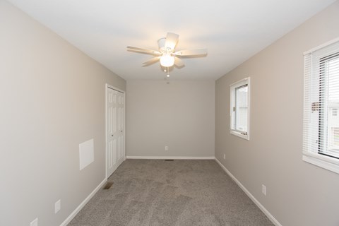 an empty bedroom with a ceiling fan and a door