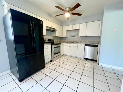a kitchen with white cabinets and a black refrigerator