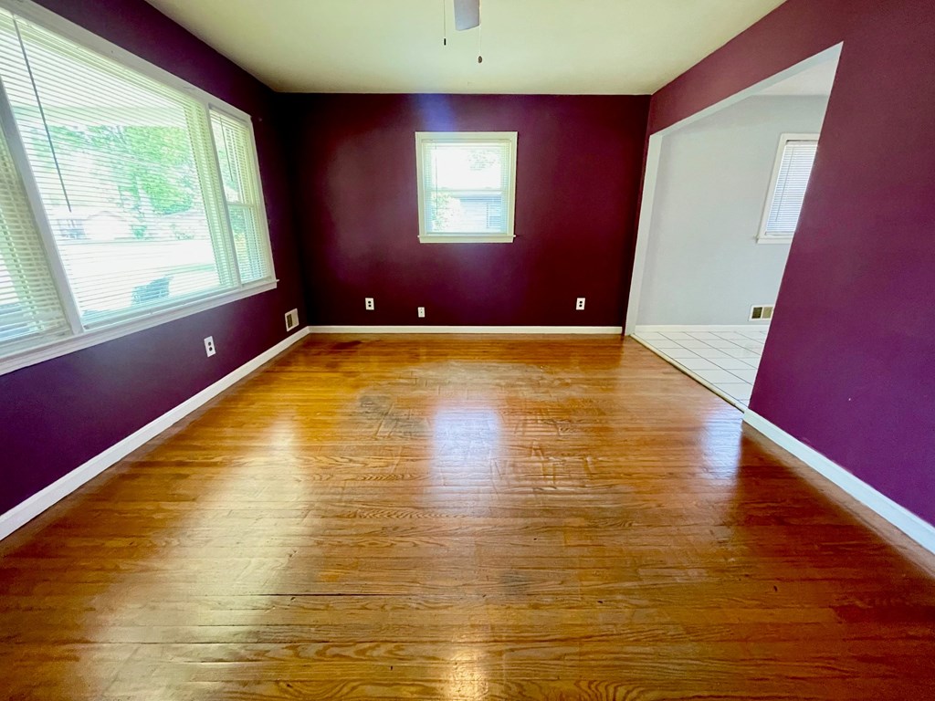an empty living room with purple walls and wooden floors